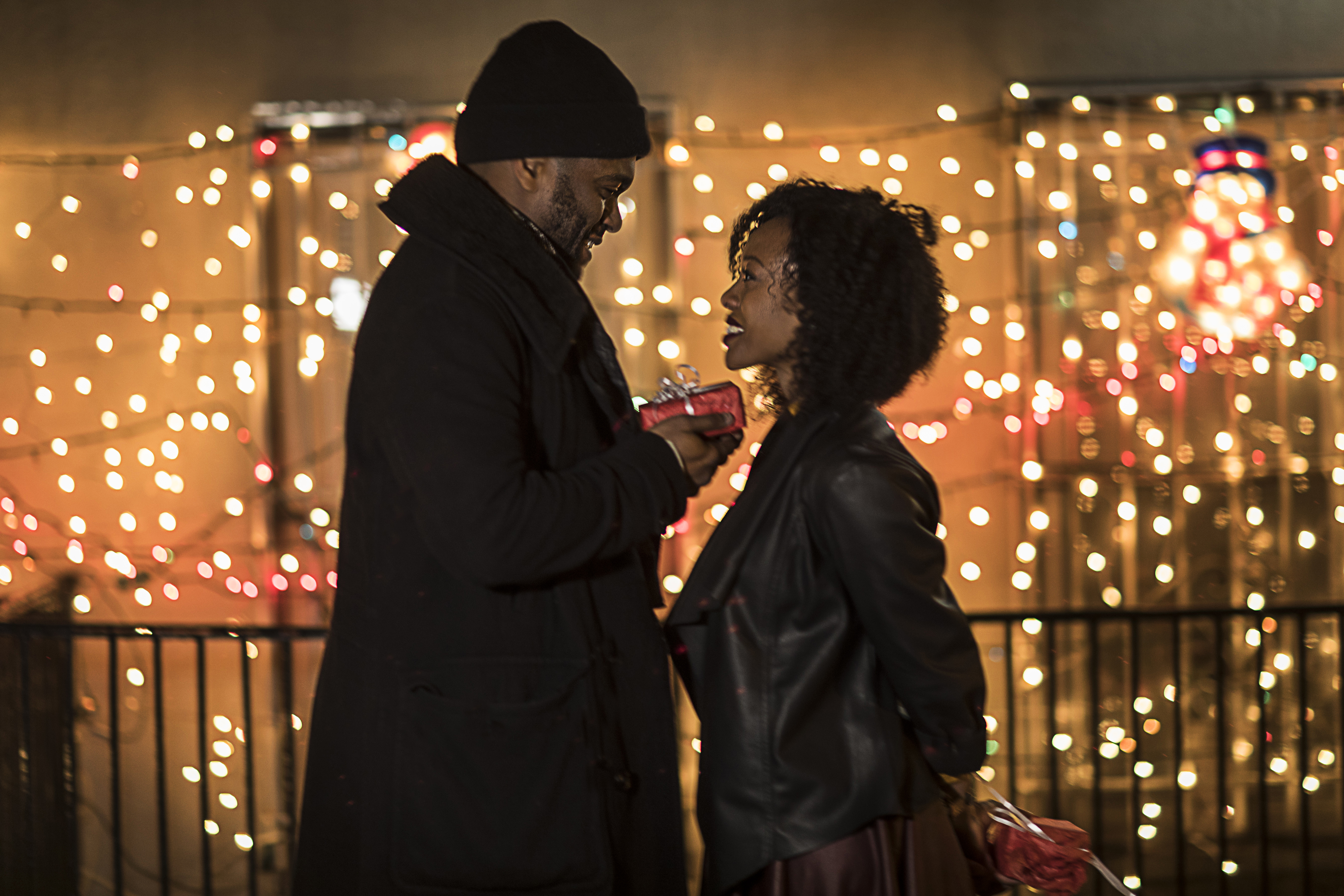 Romantic couple handing christmas gifts at night, New York, USA