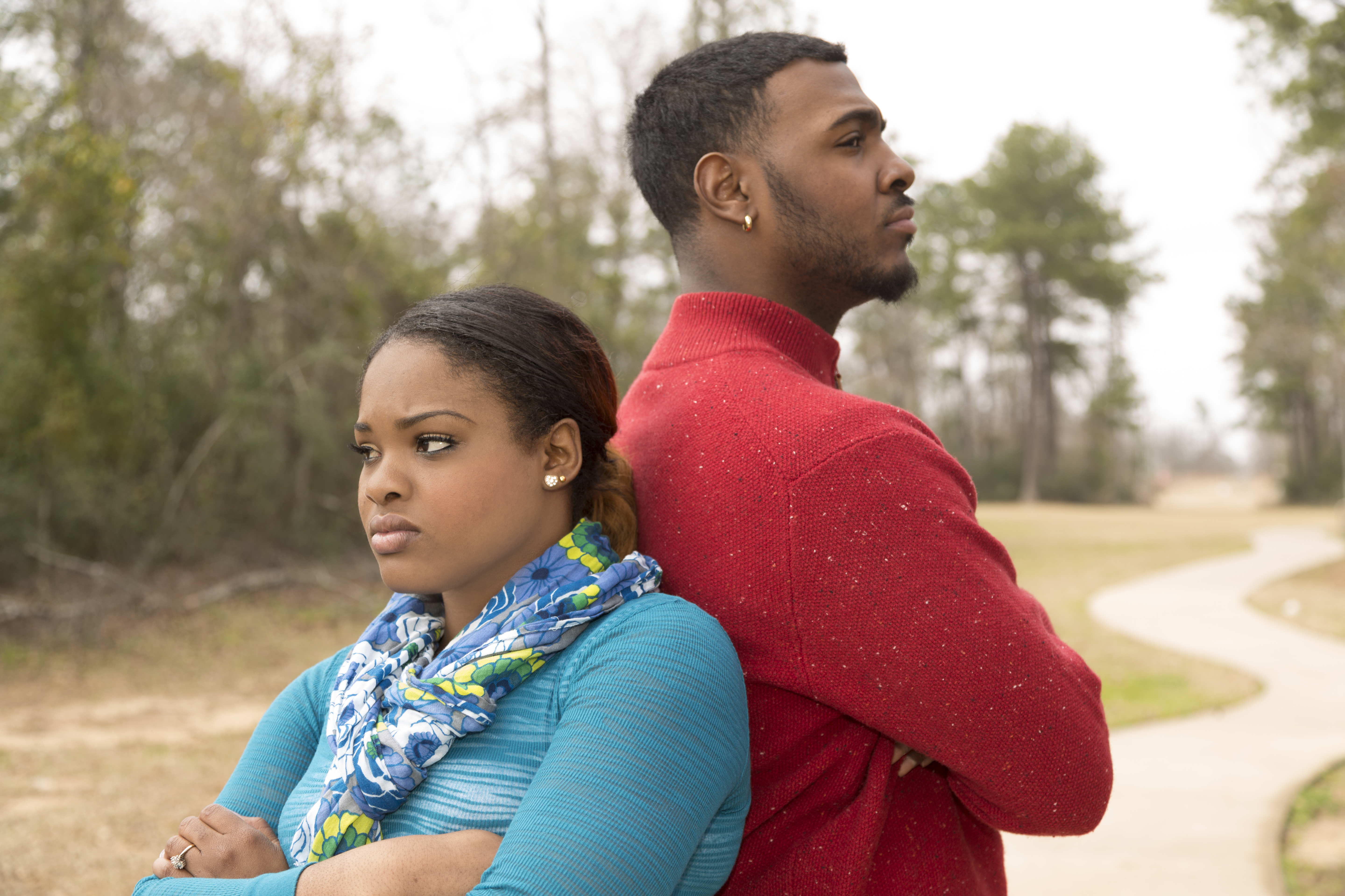 Sad African descent couple in park setting after argument.