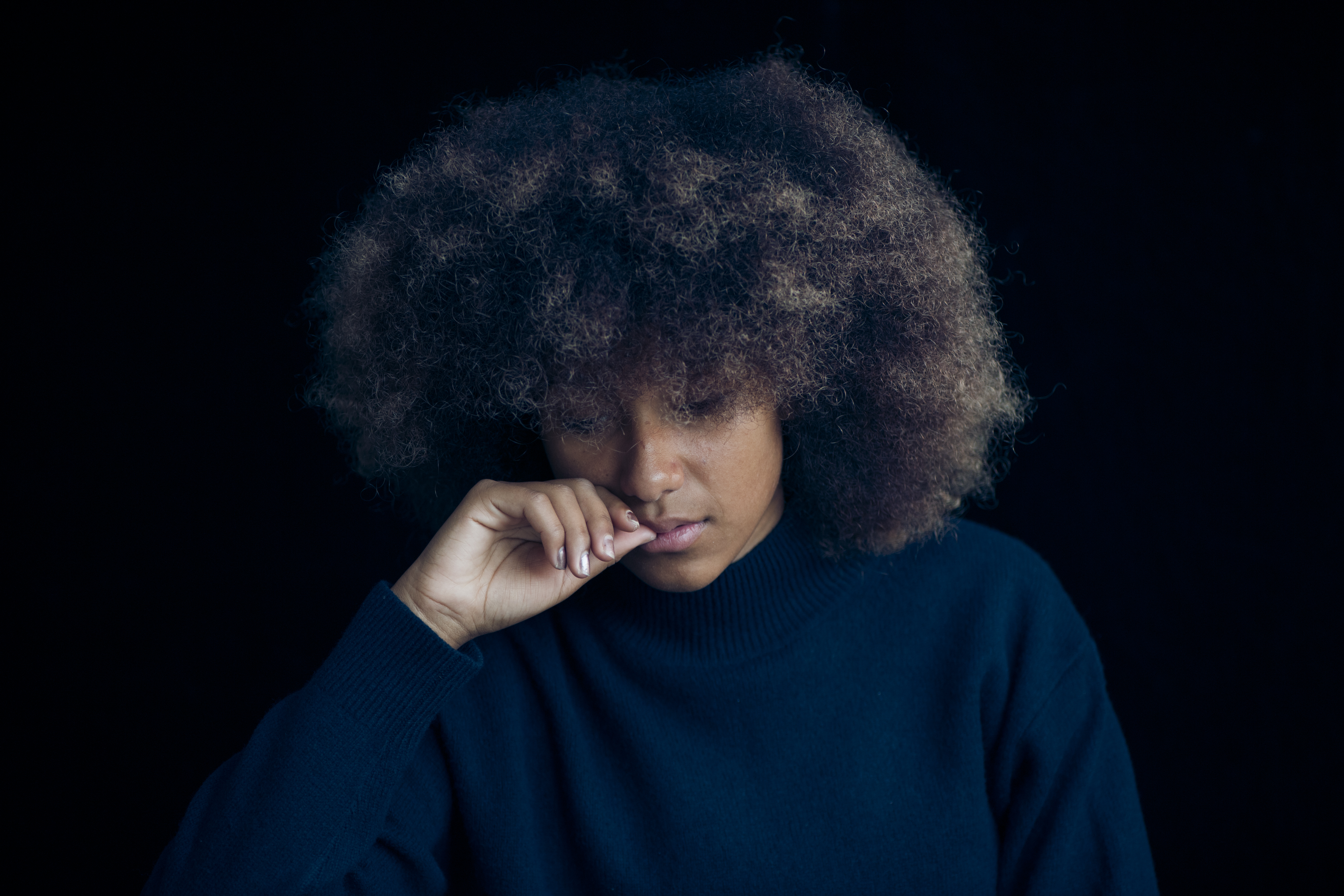 Mixed race teenage girl wearing a blue jumper with an afro haircut