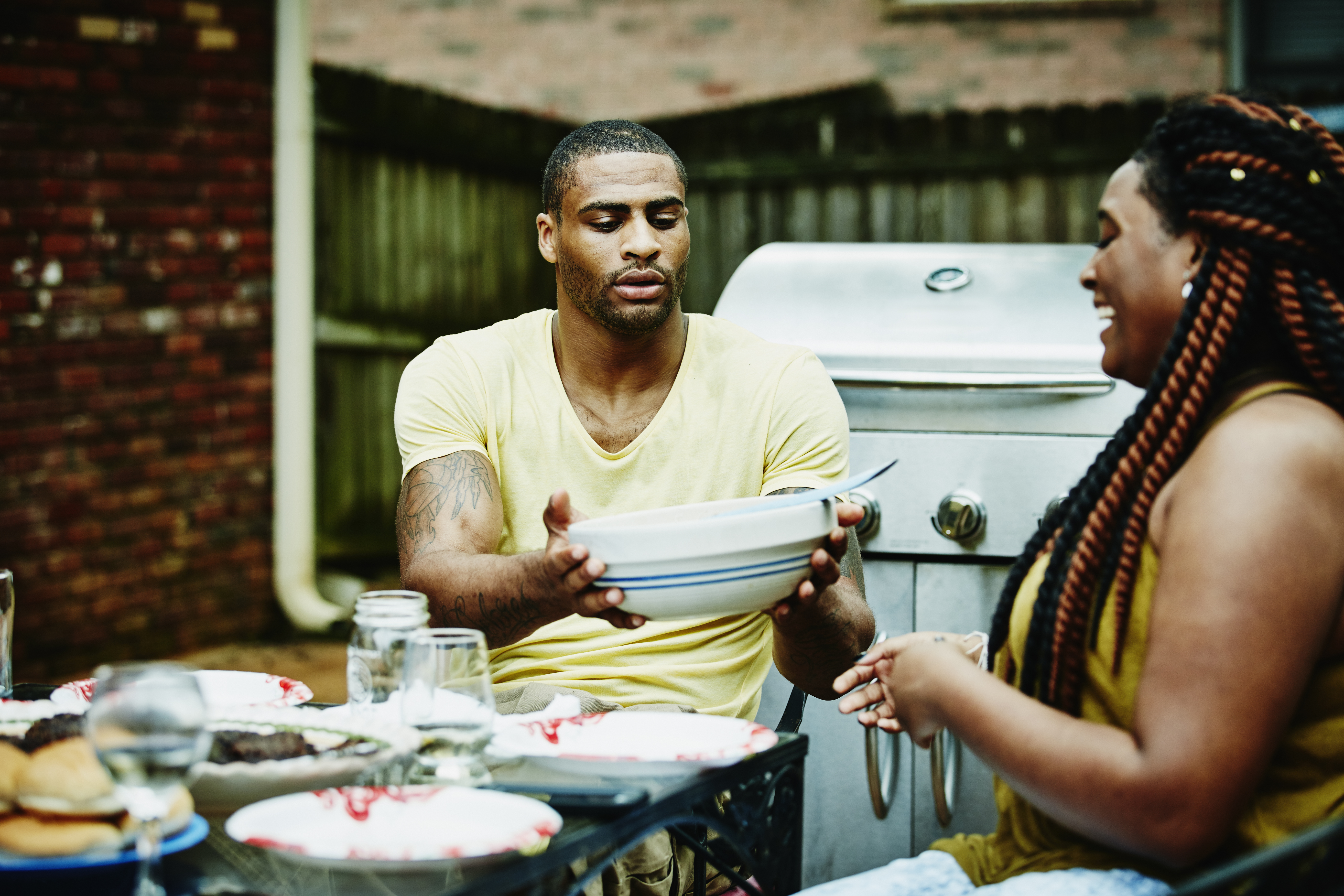 Man passing woman bowl of salad during dinner