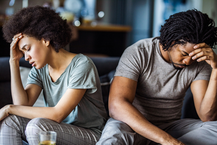 Young black couple feeling sad after arguing on sofa at home.
