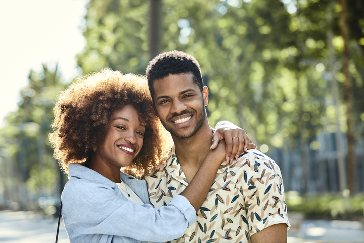 Smiling woman embracing man on sidewalk in city