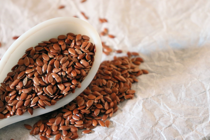 Close-up of flax seeds in a ceramic spoon against white background