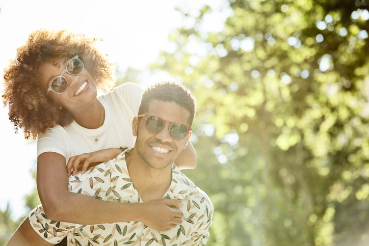 Happy couple enjoying piggyback ride on sunny day