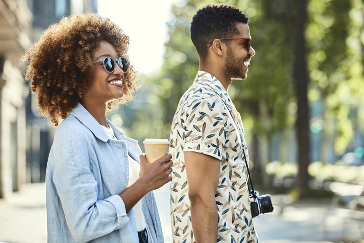 Happy tourist couple walking on sidewalk in city