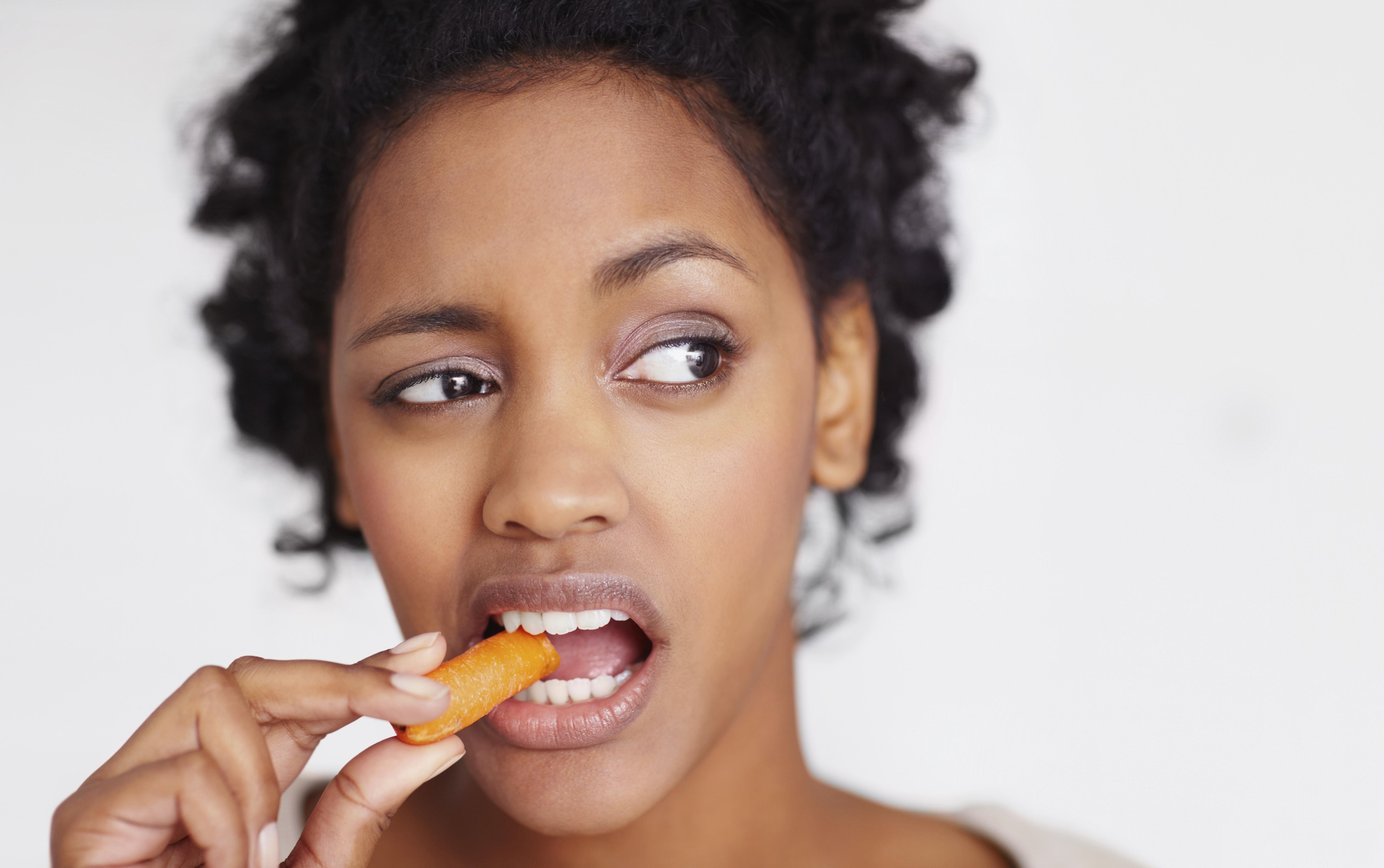 Unhappy woman eating a carrot