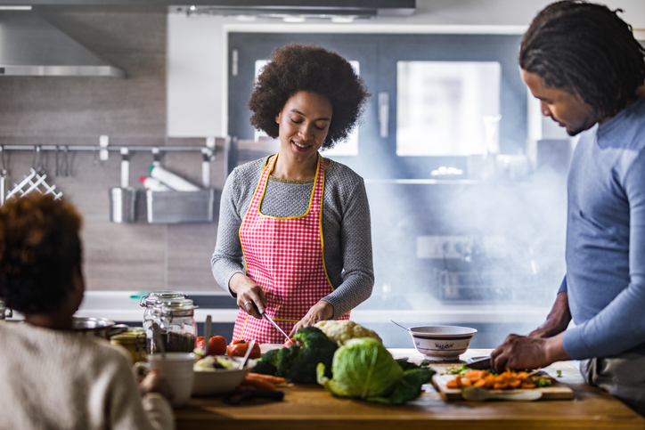 Happy black family preparing meal in the kitchen.