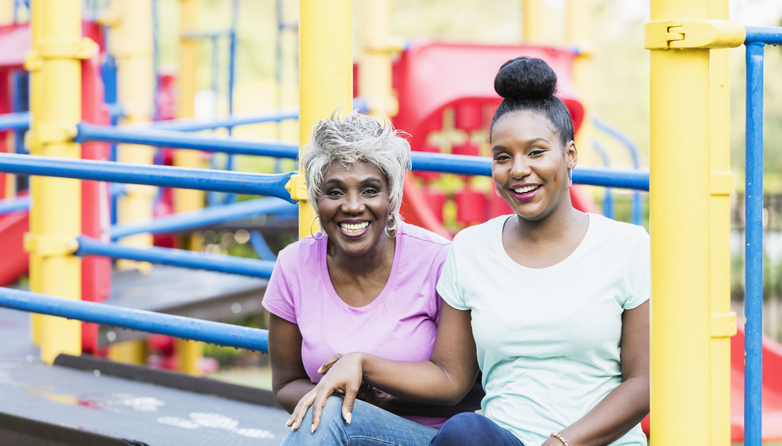 Senior woman and adult daughter sitting on playground