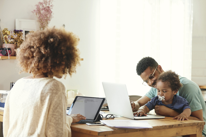Father and mother working while sitting with son
