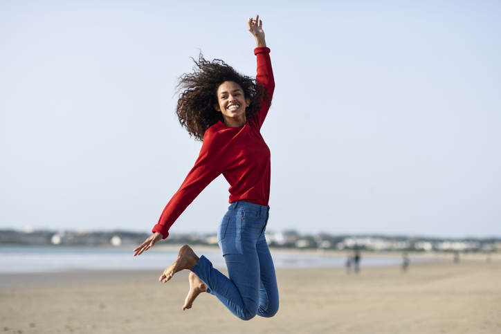 Carefree young woman jumping on the beach