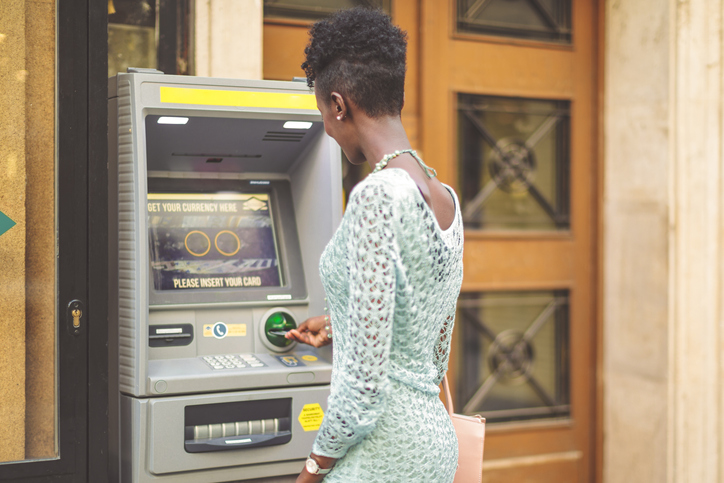 Young woman is withdrawing cash from an atm machine