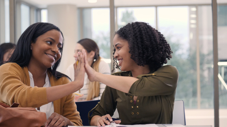 College friends high five while studying