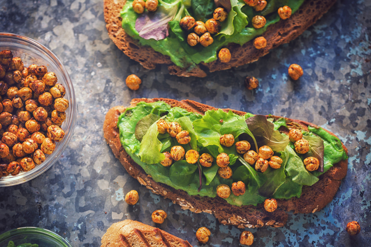 Avocado toast topped with hummus, salad and crispy roasted chickpeas