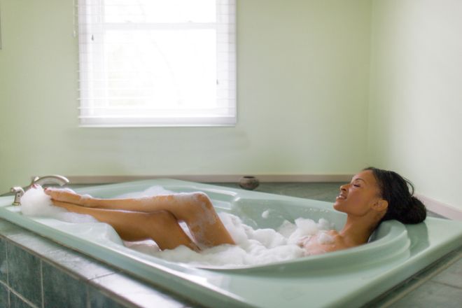 Young woman relaxing in bubble bath with feet up