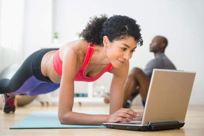 Woman using computer and doing push-ups in gym