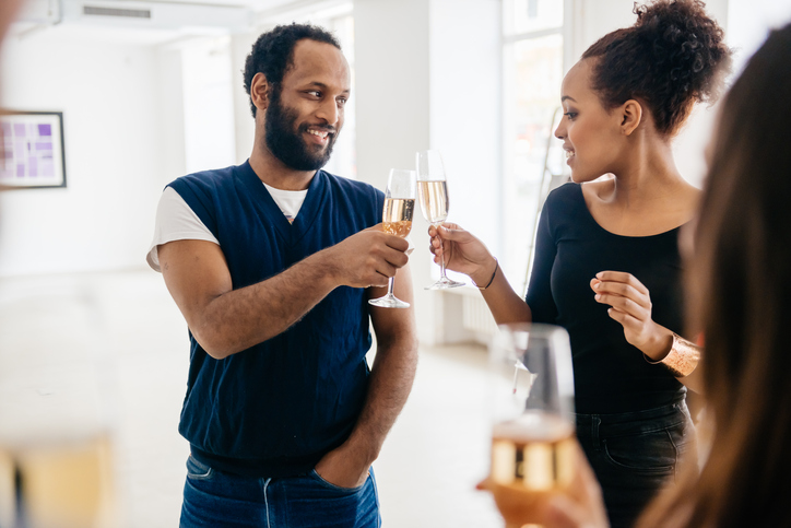 Two african visitors touching glasses during a gallery opening