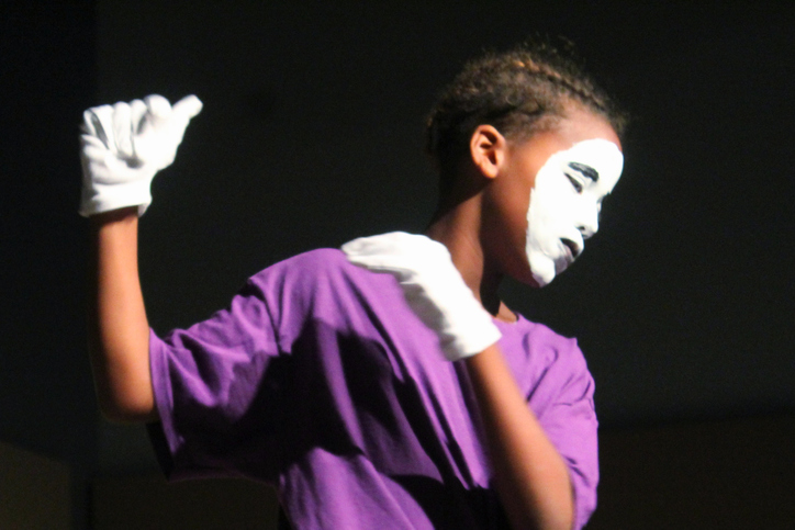 Boy With Painted Face Dancing Against Black Background