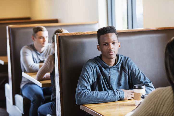 Teenage boy sitting in restaurant booth, with friend