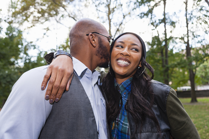 Man kissing womans cheek in park