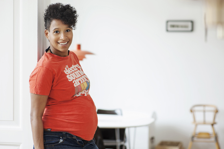 Pregnant woman leaning against doorway