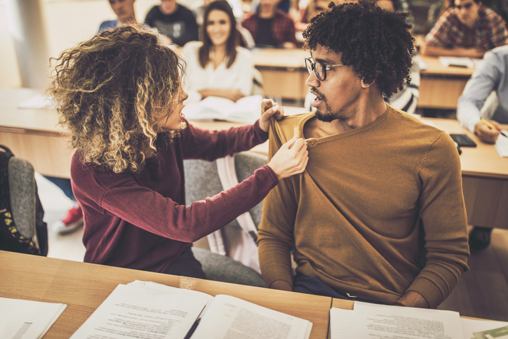 Frustrated female student arguing with her shocked boyfriend in the classroom.