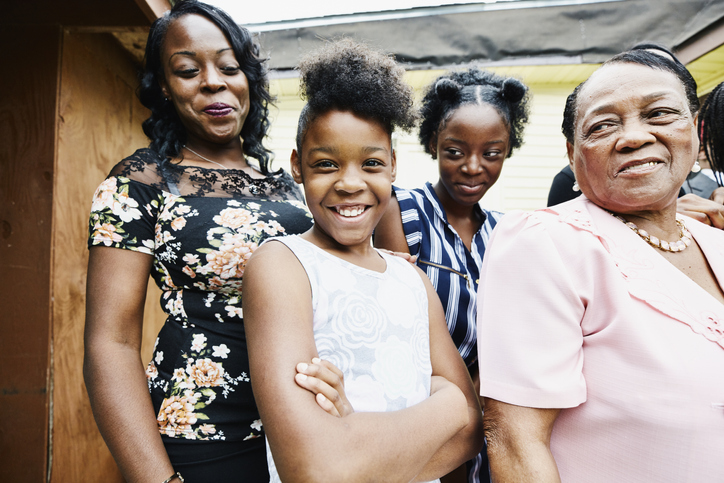 Portrait of smiling granddaughters standing with mother and grandmother