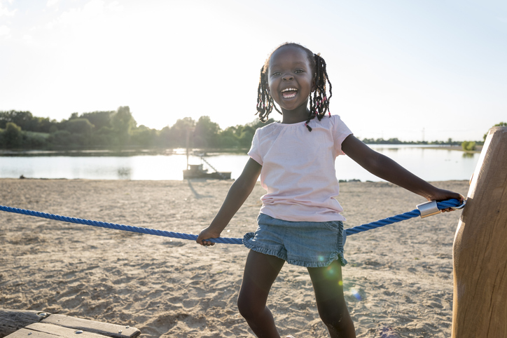 children portrait: laughing cute girl at playground, looking at camera
