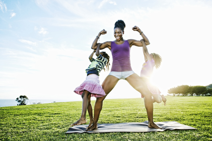 Woman lifting children with biceps in park