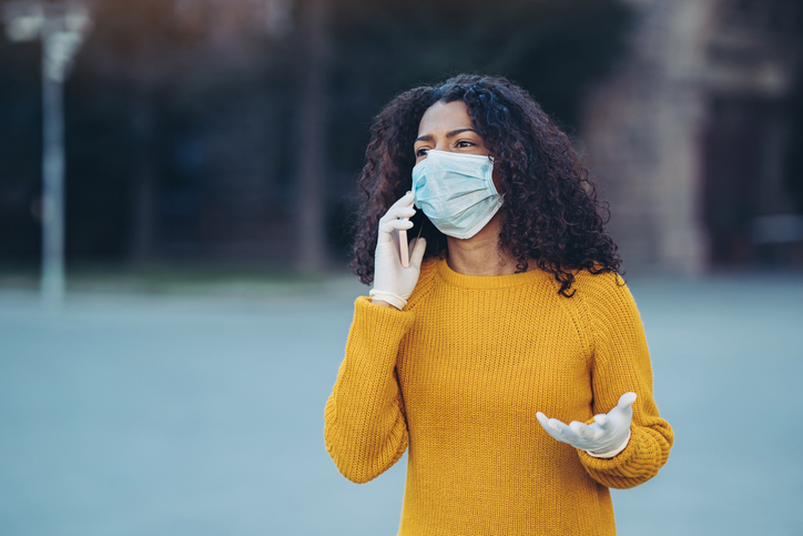 Worried young woman talking on the phone during flu epidemic