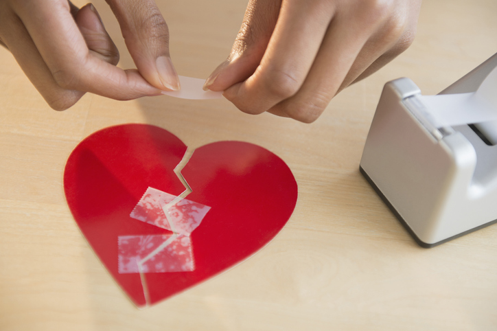 Mixed race woman taking broken paper heart