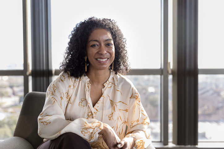 Female psychiatrist relaxes in office and smiles for photo