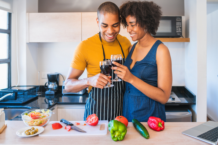 Smiling Couple Toasting Drink While Standing In Kitchen