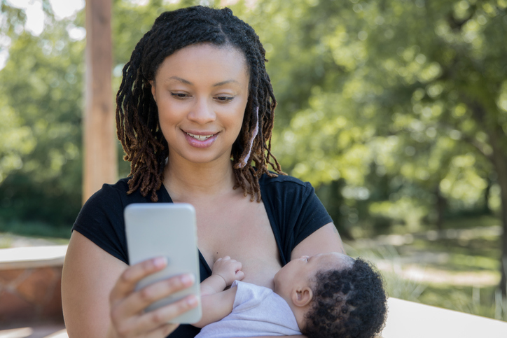 Mother holding son and using mobile phone