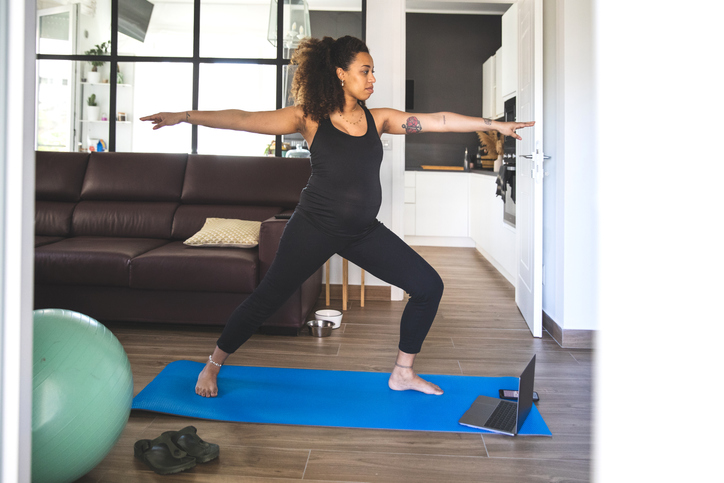 Pregnant woman practicing Yoga with online video class