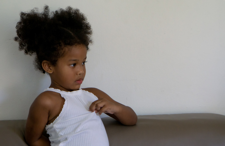 Thoughtful Girl Sitting Against Wall