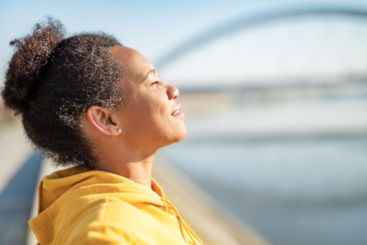 Beautiful African American woman enjoying the morning sunlight and meditating.