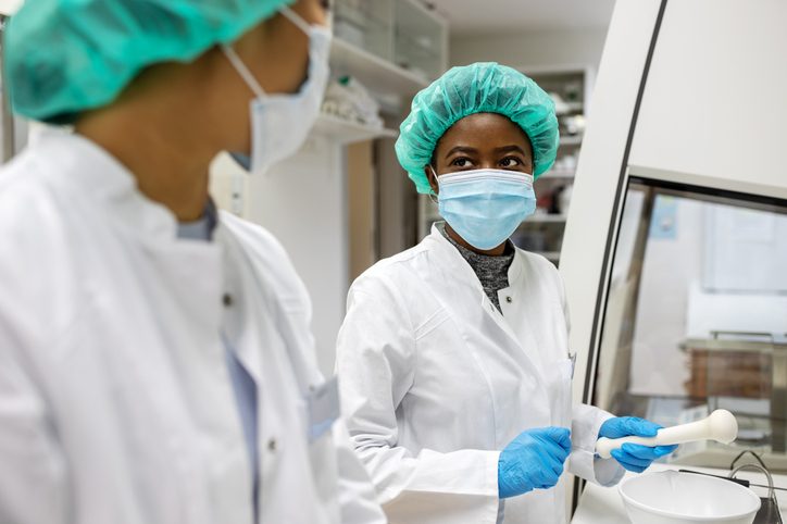Scientists discussing while making medicine at laboratory