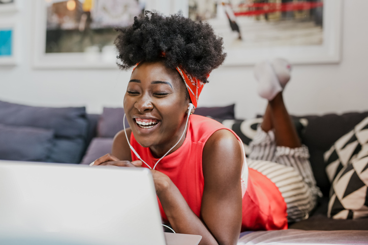 A young black woman working on her laptop in her apartment.