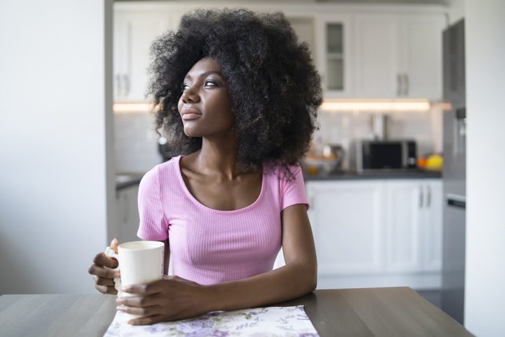 African woman drinking coffee home alone