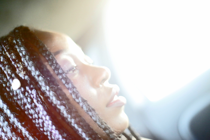 Close-Up Of Woman With Braided Hair Against Window