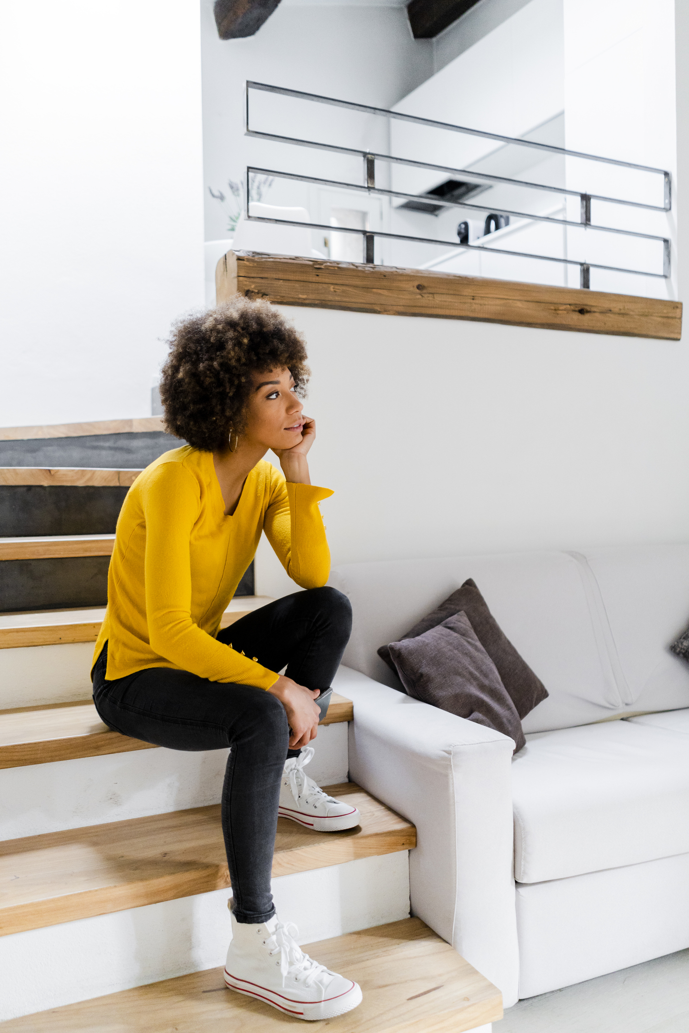 Pensive young woman sitting on stairs at home