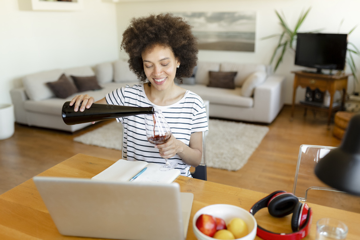 Cheerful young African American woman having a drink at home