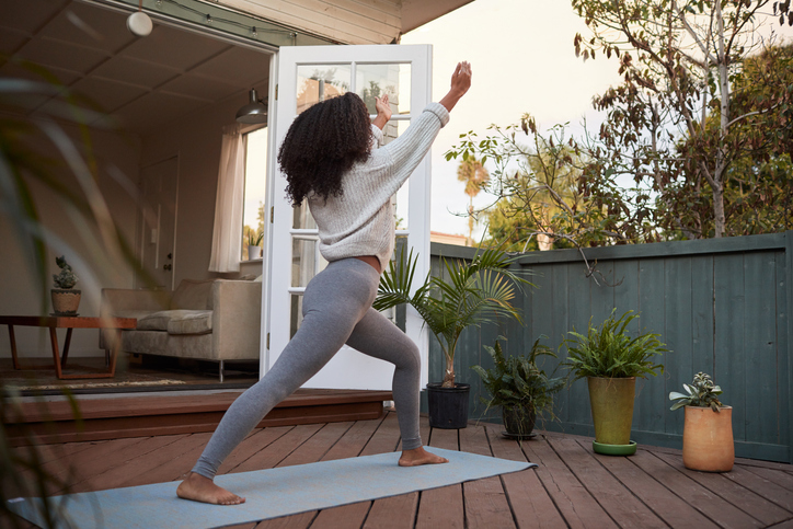 Young woman doing the crescent lunge pose on her patio