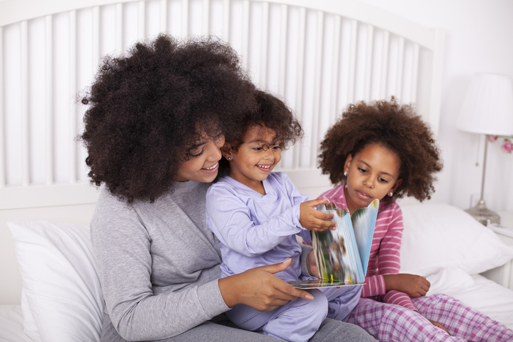 Mother with daughters reading books in bed