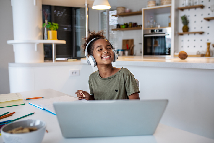 Young girl at home studying with laptop