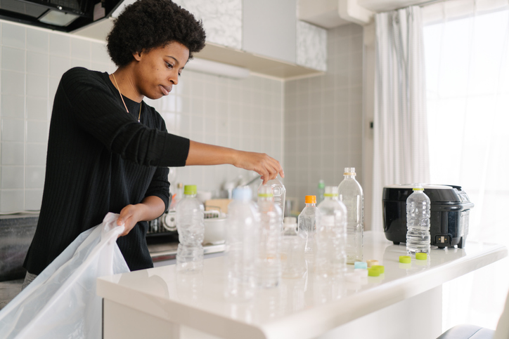 Woman separating wastes and pet bottles at home for recycling