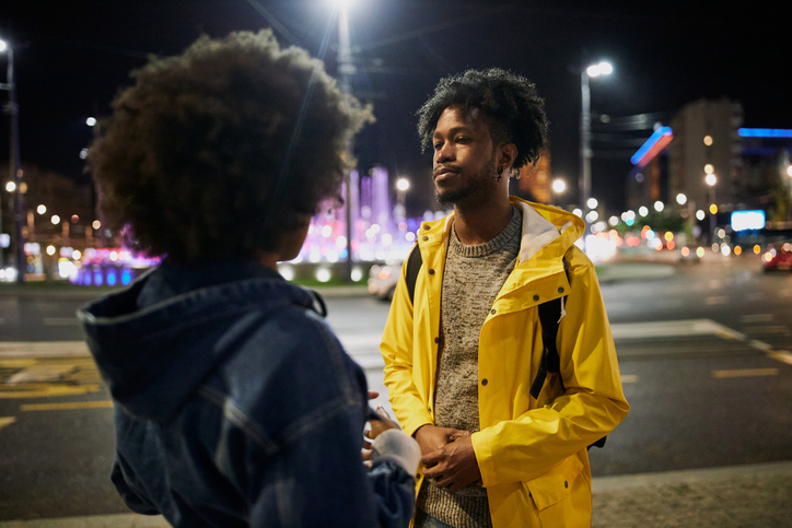 Young African American traveling couple standing on the street at night