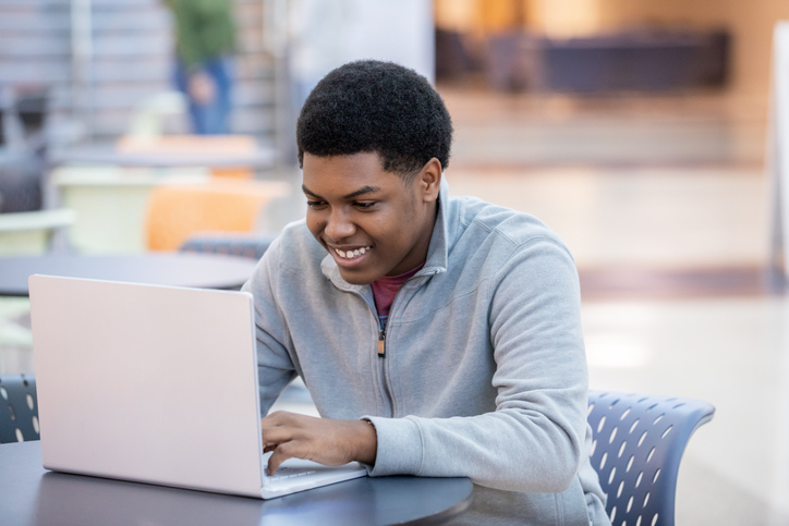 Young adult male working on assignment on laptop