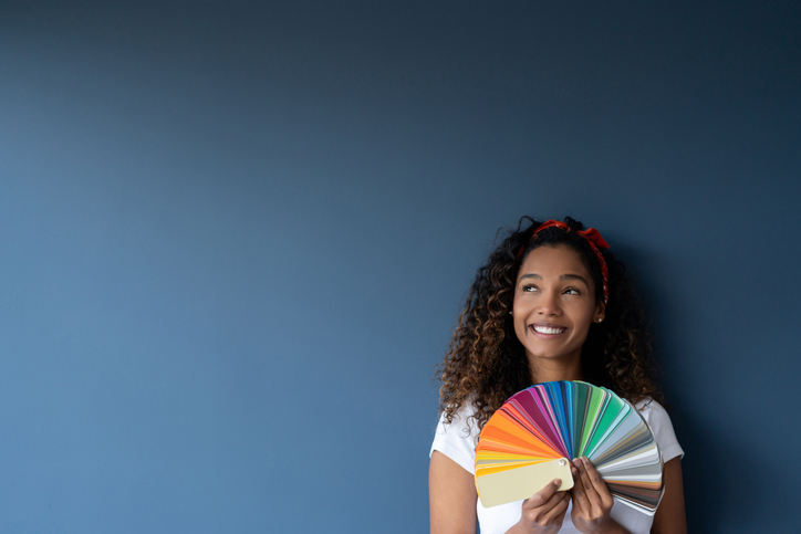 Thoughtful woman painting her home and holding a color palette