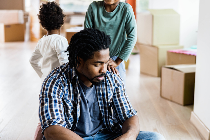 Worried African American single father with his kids at new apartment.